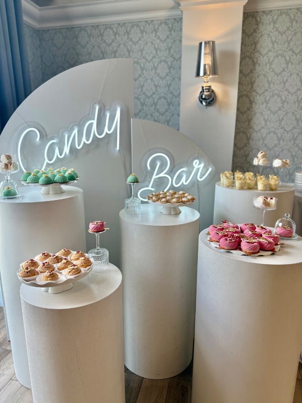Candy bar z neonem i deserami na białych postumentach