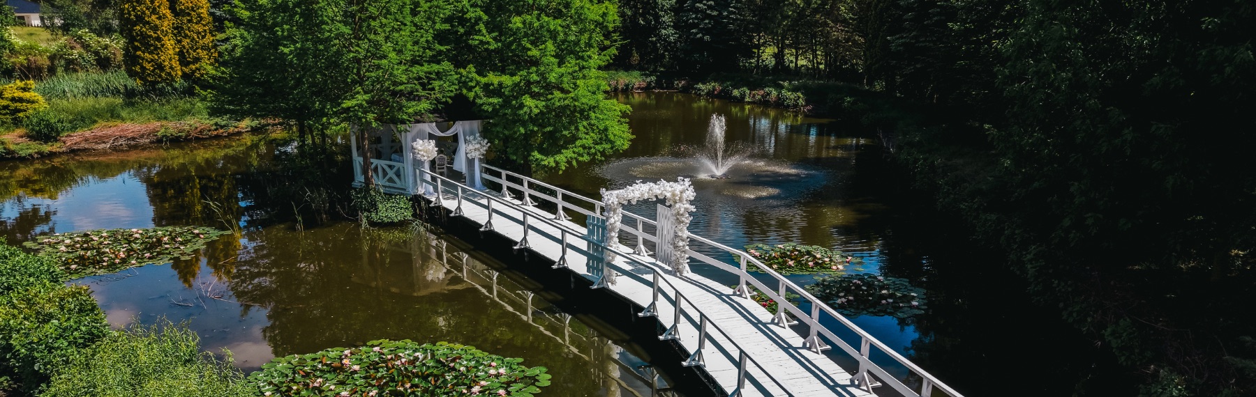 Ogród Hotelu Toscania z lotu ptaka - mostek nad stawem i miejsce ceremonii ślubnej z krzesłami dla gości