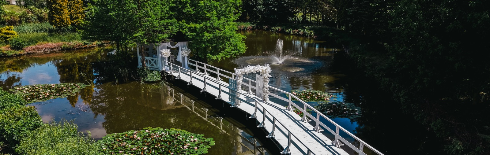 Mostek nad stawem z altaną ślubną w ogrodzie Hotelu Toscania